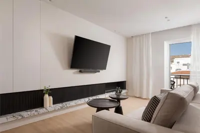 a living room with a couch and a tv on a wall at Glyfada Prime Living in Athens