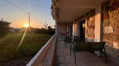 a row of chairs sitting on a porch with the sunset at Beach house in the heart of Athens Riviera in Athens
