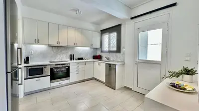 a kitchen with white appliances and a table in it at Beach house in the heart of Athens Riviera in Athens