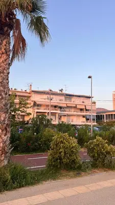 a large building with a palm tree in front of it at Beach house in the heart of Athens Riviera in Athens