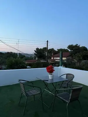 a table with two chairs and a vase of flowers on a balcony at Minimal Above in Paianía