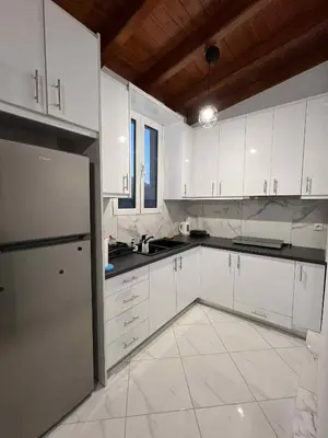 a white kitchen with white cabinets and a refrigerator at Minimal Above in Paianía