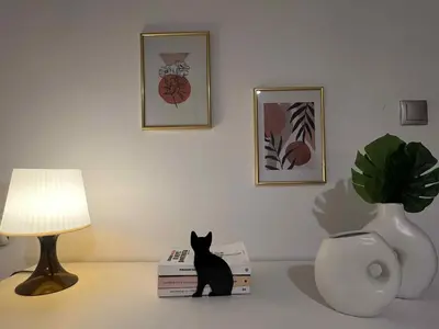 a black cat sitting on a table next to a lamp at Minimal Above in Paianía