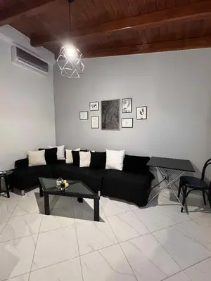 a living room with a black couch and a table at Minimal Above in Paianía