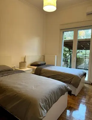 two beds in a bedroom with a large window at Modern Glyfada Apartment Sleeps 6, 5min Walk to Beach in Athens