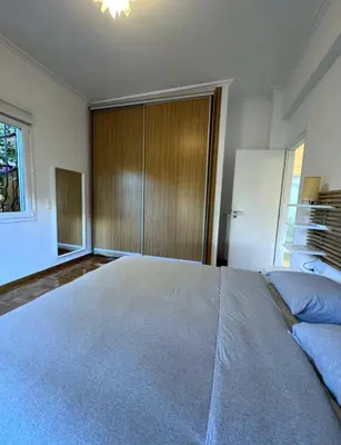 a bedroom with a large bed with a wooden closet at Modern Glyfada Apartment Sleeps 6, 5min Walk to Beach in Athens