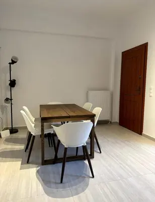 a dining room with a wooden table and white chairs at Modern Glyfada Apartment Sleeps 6, 5min Walk to Beach in Athens