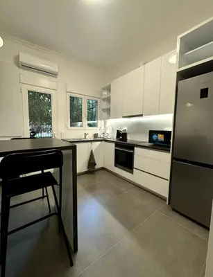 a kitchen with white cabinets and a black counter top at Modern Glyfada Apartment Sleeps 6, 5min Walk to Beach in Athens