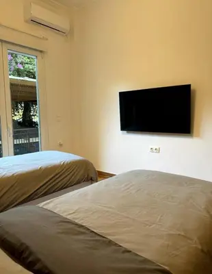 a bedroom with two beds and a flat screen tv on the wall at Modern Glyfada Apartment Sleeps 6, 5min Walk to Beach in Athens