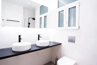 two sinks in a white bathroom with mirrors at Syntagma square 25sqm Cozy studio in Athens
