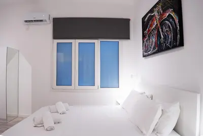 a white bedroom with a large bed with white pillows at Syntagma square 25sqm Cozy studio in Athens