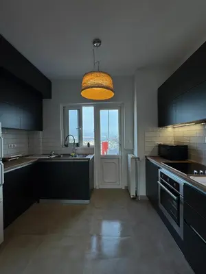 a kitchen with black cabinets and a large window at Captain's flat in Piraeus