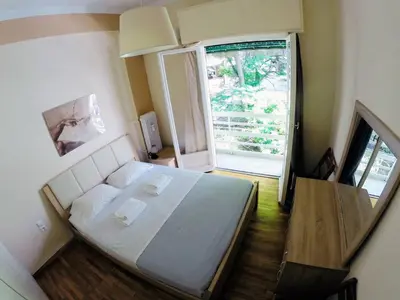 a small bedroom with a bed and a large window at Acropolis Cozy Apartment in Athens