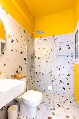 a bathroom with a toilet and a rock wall at Acropolis Lane in Athens
