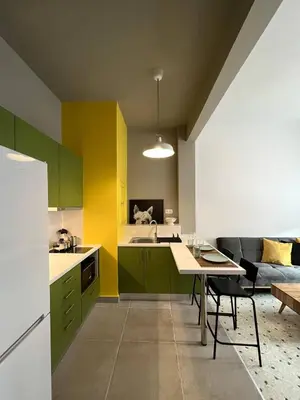 a kitchen with green and yellow cabinets and a table at Acropolis Lane in Athens