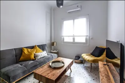 a living room with a gray couch and yellow pillows at Acropolis Lane in Athens