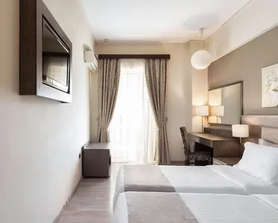 a bedroom with a bed and a desk and a window at Acropolis Select in Athens