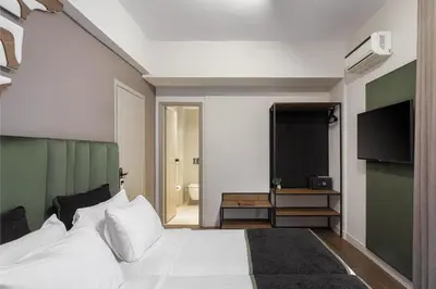 a bedroom with a white bed and a flat screen tv at Acropolis Select in Athens
