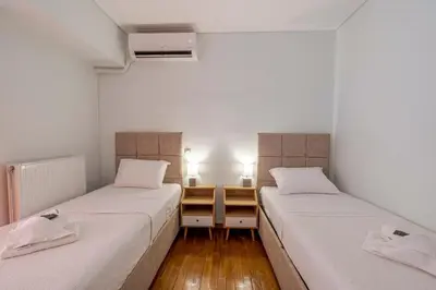 two beds in a room with white walls and wooden floors at Comfortable Family Apartment,3 stops to Acropolis in Athens