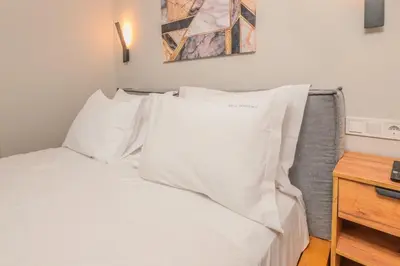 a bed with white sheets and pillows next to a table at Pythagorio Apartment in Piraeus