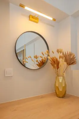 a mirror on a wall with a vase on a table at Pythagorio Apartment in Piraeus
