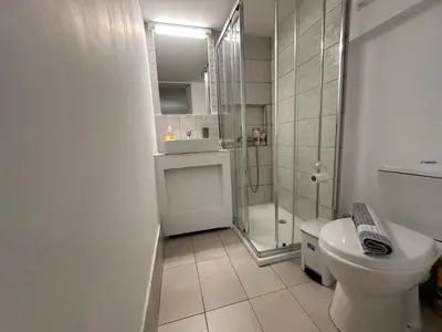 a white bathroom with a shower and a toilet at Ground floor next to Errikos Ntinan and Erithros in Athens