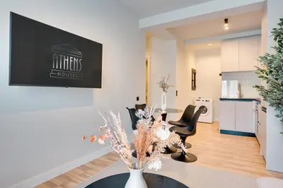 a living room with a table and chairs and a kitchen at Skyline Spa Athens 110 in Athens