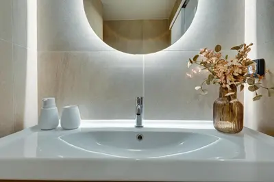 a bathroom sink with a mirror and a vase with flowers at Skyline Spa Athens 110 in Athens