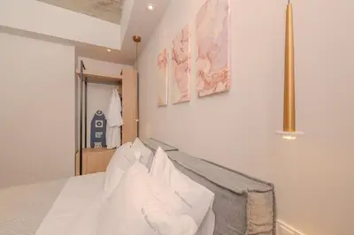 a bedroom with a bed with white sheets and pillows at Pink Season Apartment in Piraeus