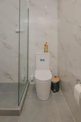 a bathroom with a toilet and a glass shower at Pink Season Apartment in Piraeus