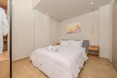a white bedroom with a large white bed at Saint Mykonos Apartment in Piraeus