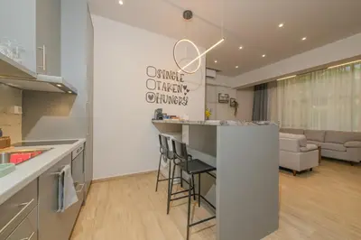 a kitchen with a bar and a living room at Saint Mykonos Apartment in Piraeus
