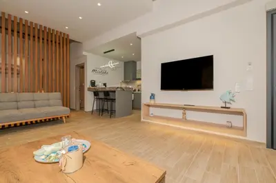 a living room with a couch and a tv on a wall at Port of Crete Apartment in Piraeus