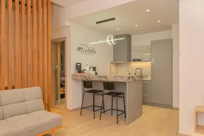 a kitchen with a counter and a bar with stools at Port of Crete Apartment in Piraeus