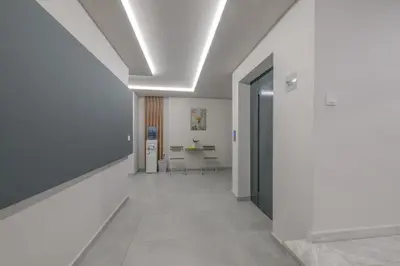 a hallway with white walls and a room with a table at Dear Paris Apartment in Piraeus