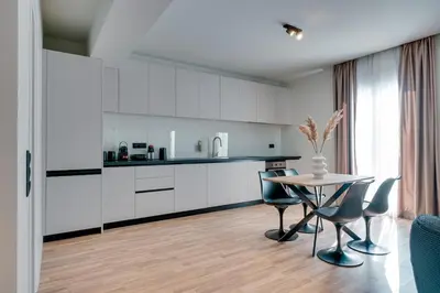 a kitchen with white cabinets and a table and chairs at Skyline Spa Athens 420 - 2bd in Athens
