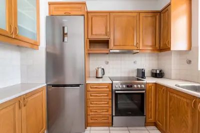 a kitchen with wooden cabinets and a stainless steel refrigerator at Family Escape in Chalandri by UPSTREET in Athens