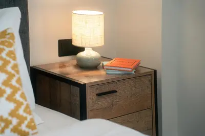 a lamp on a wooden nightstand with a book at Skyline Spa Athens 410 - 2bd in Athens