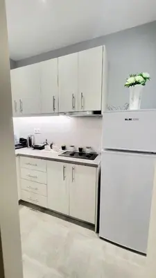 a kitchen with white cabinets and a white refrigerator at Luminous Apartment in Mesochórion