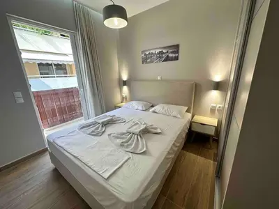a bedroom with a bed with white sheets and a window at Downtown modern apartment in Athens