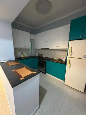 a kitchen with blue cabinets and a white refrigerator at Lilia Apartments in Athens