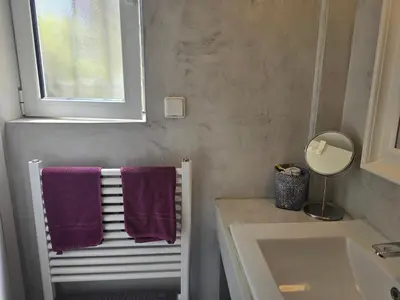 a bathroom with purple towels on a radiator and a window at Lida Garden Loft in Anavissos