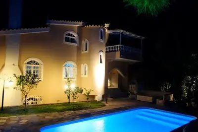 a house with a swimming pool in front of it at night at Villa Dendron in Aghia Marina