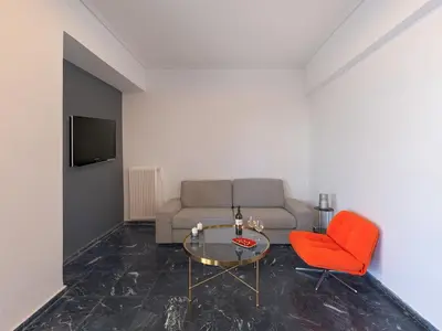 a living room with a couch and a table and a red chair at Top-Floor Modern Penthouse with Stunning Sea Views in Piraeus