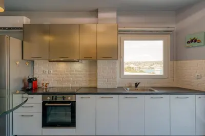 a kitchen with white cabinets and a window at Royal Fig Apartment Porto Rafti in Porto Rafti