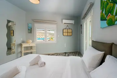 a bedroom with a white bed and a window at Royal Fig Apartment Porto Rafti in Porto Rafti