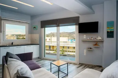 a living room with a couch and a tv at Royal Fig Apartment Porto Rafti in Porto Rafti