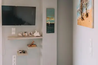 a living room with a flat screen tv on a wall at Royal Fig Apartment Porto Rafti in Porto Rafti