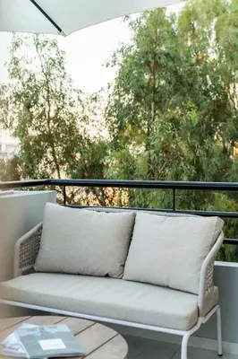 a couch on a balcony with a view of trees at Luxury Modern Apartment with Stunning Glyfada View in Athens