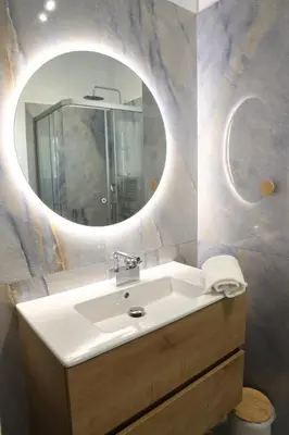 a bathroom with a sink and a round mirror at Serene & Stylish apt by GHH in Athens
